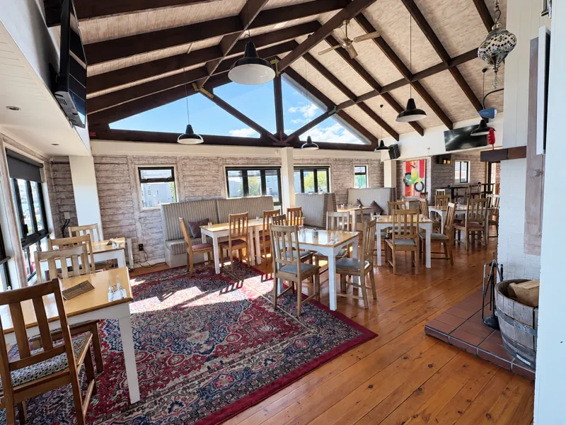 Lakefront’s sunny dining room, with timber beams and tables ready for guests
